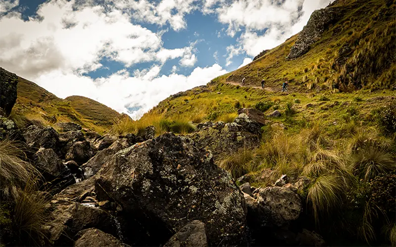 Cyclist on rock-wall section of Lamay MTB route (Peru Biking Tours)
