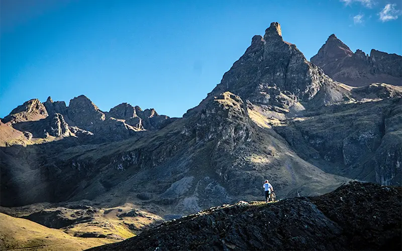 Distant Andes peaks with trail silhouette on high mountain plateau (Peru Biking Tours)