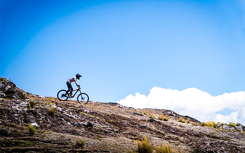 Cyclist riding across a highland plateau near Pisac on a mountain biking tour (Peru Biking Tours)