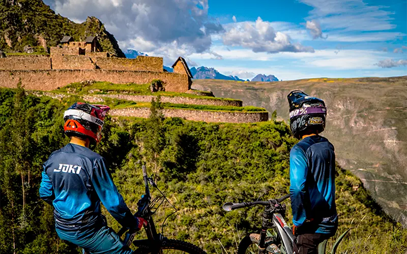 Cyclists riding past ancient Inca ruins along the Perolniyoc trail route (Peru Biking Tours)